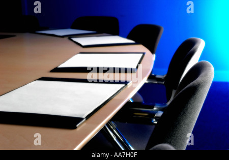 Schwarze Stühle und Lederblotter auf einem Holztisch in einem leeren Sitzungssaal Stockfoto