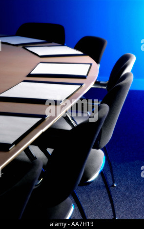 Schwarze Stühle und Lederblotter auf einem Holztisch in einem leeren Sitzungssaal Stockfoto