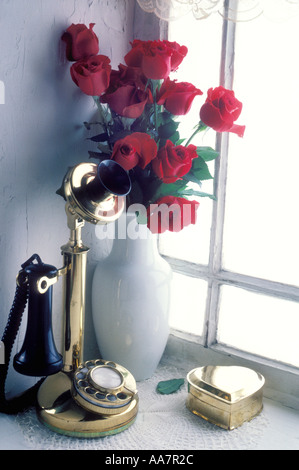 Kerze-Telefon im Fenster mit Vase mit roten Rosen Stockfoto