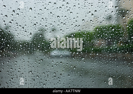 Blick auf die Straße durch ein nasses Glas eines Fensters im regnerischen Wetter abstrakten Hintergrund mit Wassertropfen Stockfoto