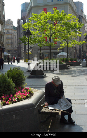 Serbien Belgrad Kneza Mihailova Fußgänger Straße Alter Mann liest Zeitung mit Pflanzen und Bäumen in Bkgd vertikale Stockfoto