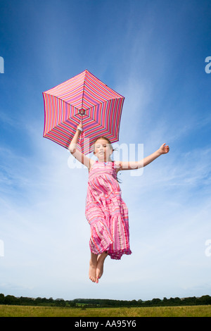 Mädchen mit Regenschirm in die Luft springen Stockfoto