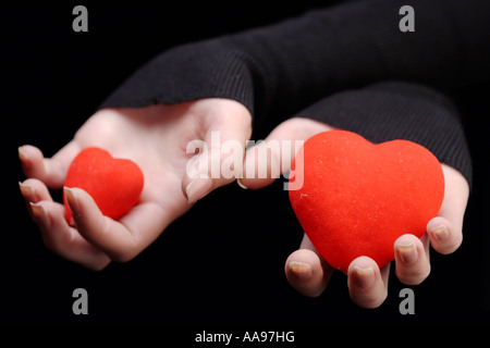 Hände halten zwei rote Herzen Stockfoto