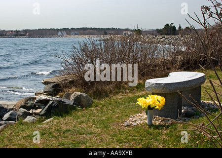 Blumen am Denkmal für ein Anwohner bei einer Bank mit Blick auf den Ozean Stockfoto