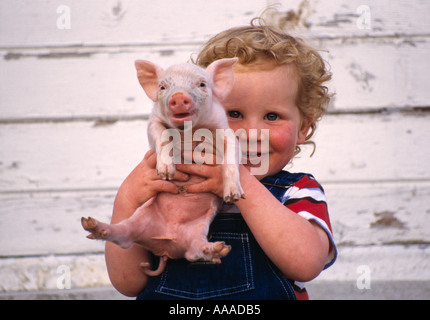 Landwirtschaft - leben auf dem Bauernhof kleiner Junge hält ein Ferkel / Fort Atkinson, Wisconsin, USA. Stockfoto