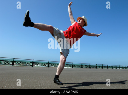 Ein übergewichtiger Mann mittleren Alters dabei ungeschickt hohen munter Tanz-Routine auf Brighton seafront Stockfoto