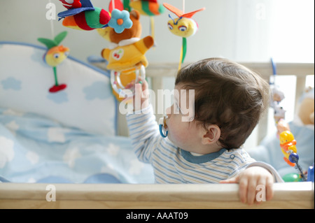 Baby Junge spielt mit einem Handy in eine Krippe spielen Stockfoto