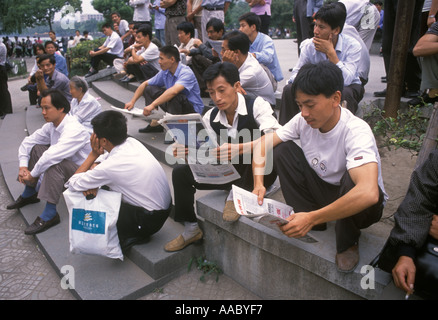 China Männer lesen Zeitung nach der Arbeit Hocken sitzen in Nummer 1 Volkspark Hangzhou Provinz Zhejlang . 2000er Jahre 2001 HOMER SYKES Stockfoto