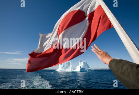 Grönland-Ilulissat-Passagier streckt Hand grönländischen Flagge flattert im Wind von der Arctic Umiaq Line Fähre Segeln vorbei an Stockfoto