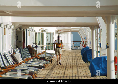 An Bord eines Mittelmeer Kreuzfahrtschiff liner auf See ein Mann nimmt Spaziergang am frühen Morgen allein um passagierdeck vor der Liegestühle packte erhalten Stockfoto