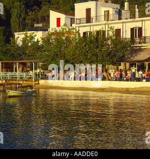 Menschen, die späte Nachmittagssonne auf Veranda am Ufer Taverne in Agnotas auf Insel Skopelos der griechischen Inseln genießen Stockfoto