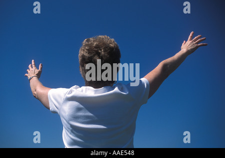 Frau Arme angehoben, winken und blickte zu blauen Himmel Stockfoto