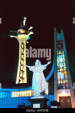 Post moderne St. Bonaventura römisch-katholische Kathedrale Banja Luka beleuchtet bei Nacht und Jesus-Christus-Statue mit ausgestreckten Armen Stockfoto