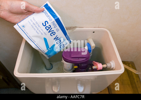 Hand, die Platzierung von Hippo Severn Trent Saveaflush Wasserbeutel im Spülkasten UK Stockfoto