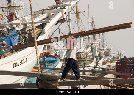 Mann entladen Holz aus einem hölzernen Segeln Schiffe oder Prahu aus Sulawesi im alten Hafen Sunda Kelapa Jakarta Stockfoto