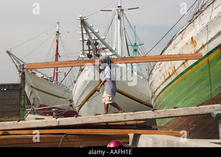 Der Mensch entladen Holz aus einem hölzernen Segelschiff oder Prahu aus Sulawesi im alten Hafen Sunda Kelapa Jakarta Stockfoto