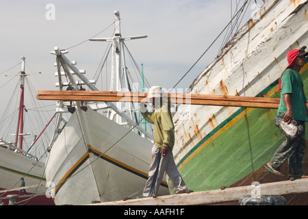 Mann entladen Holz aus einem alten Stil aus Holz Segeln Schiff oder Prahu aus Sulawesi im alten Sunda Kelapa Hafen Jakarta Stockfoto