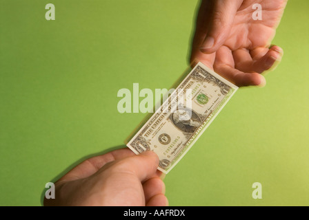 eine Person die Hände zum anderen einer Miniatur USA eine Dollarnote Darstellung die schrumpfenden US-dollar Stockfoto