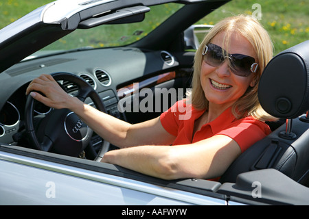 Eine ältere Frau Cabriolet Sportwagen mit Dach hinunter fahren Stockfoto