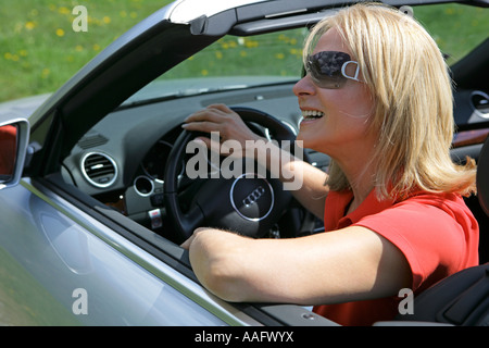 Eine ältere Frau Cabriolet Sportwagen mit Dach hinunter fahren Stockfoto