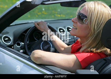 Eine ältere Frau Cabriolet Sportwagen mit Dach hinunter fahren Stockfoto