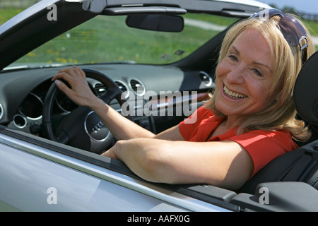 Eine ältere Frau Cabriolet Sportwagen mit Dach hinunter fahren Stockfoto