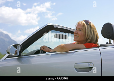 Eine ältere Frau Cabriolet Sportwagen mit Dach hinunter fahren Stockfoto