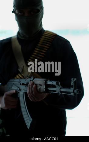 Ein Terrorist, der in einer Sturmhaube gekleidet ist und ein Kalaschnikow-Gewehr AK47 hält und einen Gürtel aus Kugeln neben einem Land rover trägt, der VOM MODELL AUS AUFGESTELLT WIRD Stockfoto