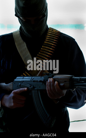 Ein Terrorist, der in einer Sturmhaube gekleidet ist und ein Kalaschnikow-Gewehr AK47 hält und einen Gürtel aus Kugeln neben einem Land rover trägt, der VOM MODELL AUS AUFGESTELLT WIRD Stockfoto