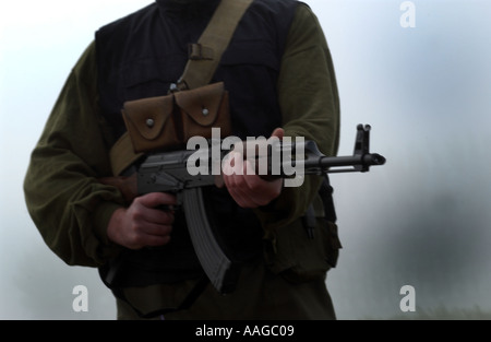 Ein Terrorist, der in einer Sturmhaube gekleidet ist und ein Kalaschnikow-Gewehr AK47 hält und einen Gürtel aus Kugeln neben einem Land rover trägt, der VOM MODELL AUS AUFGESTELLT WIRD Stockfoto