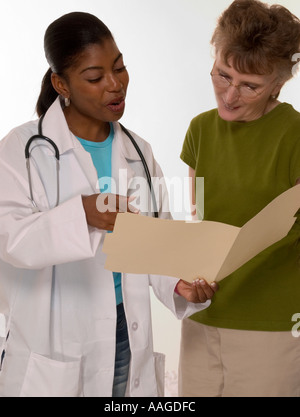 Afroamerikanischer Allgemeinarzt diskutiert Gesundheitsergebnisse mit kaukasischer Patientin während der Konsultation, USA. Stockfoto