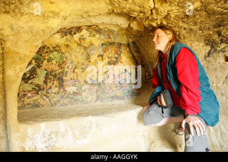 junge Frau betrachten die bemalte Wand in einer der Höhlen am Strand von Matala auf der griechischen Insel Kreta Stockfoto