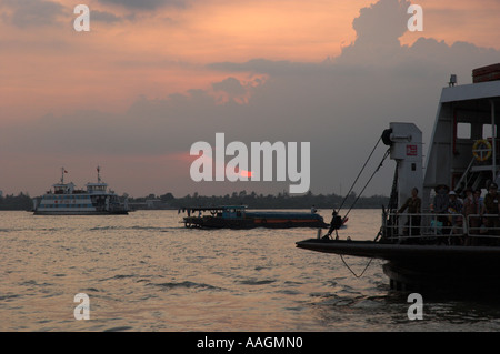 Vietnam Mekong Delta Mekong-Fluss in der Nähe von Can Tho Blick in der Abenddämmerung mit Fähren zu navigieren und die untergehende Sonne im Horizont Stockfoto