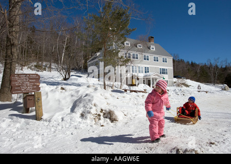 A ein junges Mädchen zieht ihren Bruder in einem Schlitten auf ein winterliches Abenteuer in der Nähe der Appalachian Mountain Club s Cardigan Lodge Stockfoto