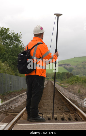 Arbeiter tragen orangefarbene Jacke mit GPS global positioning System Empfänger Umfrage eingleisigen Eisenbahn in Mitte Wales UK Stockfoto