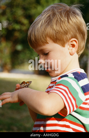 Pre-k junge 2 3 Jahr alt spielen Spiel mit Schmetterling auf Arm mit Ehrfurcht und Verwunderung Natur Naturschönheit schön kopieren Raum Closeup POV Stockfoto