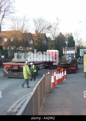 Zwei Sattelzüge auf einer Baustelle. Man hat neue Betonteile oder Träger für eine neue Eisenbahnbrücke Fertigteile. Stockfoto