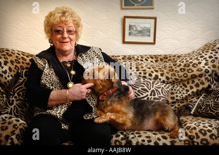 EINE WEIBLICHE RENTNER MIT EINEM LEOPARD SKIN SOFA UND WESTE WALES UK Stockfoto