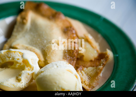 Nahaufnahme von Apfelkuchen und Vanille-Eis in einer grünen und weißen Schale auf eine weiße Küchenarbeitsplatte Stockfoto