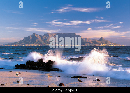Table Mountain gesehen von Blouberg Strand Kapstadt Western Cape in Südafrika mit Spritzwasser auf den Felsen im Vordergrund Stockfoto