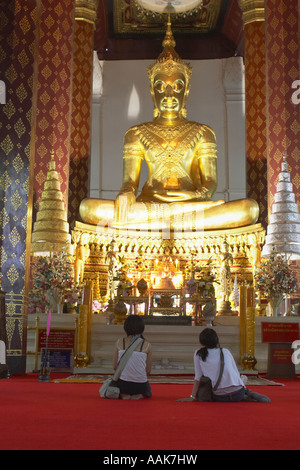 Frauen sitzen vor goldenen Statue im Wat Na Phramen Stockfoto