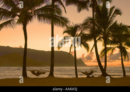 Paar in Hängematten am Strand bei Sonnenuntergang Hanalei Bay und Blick nach Bali Hai Princeville Resort Kauai Hawaii Stockfoto