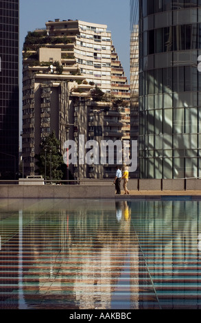 Wohnungen mit Dachgärten in ornamentalen gefliesten Pool in La Defense Paris Frankreich mit Mann und Frau zu Fuß vorbei reflektiert Stockfoto