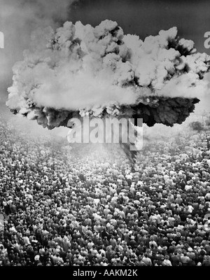 1950S 1960S ATOMBOMBE SYMBOLISCHE MONTAGE ATOMPILZ ÜBER EINE SEHR GROßE MENGE VON MENSCHEN, DIE VOR DER EXPLOSION Stockfoto