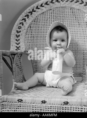 1940ER JAHREN BABY-SITTER IN WICKER SESSEL SAUGEN MILCHFLASCHE Stockfoto