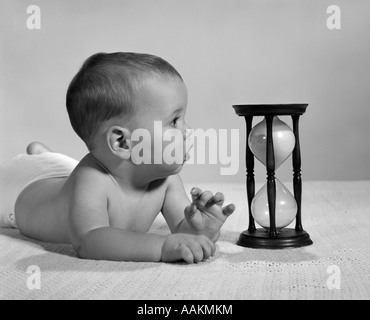 BABY LIEGEND AUF BAUCH, UNTERSTÜTZT DURCH SEINE ELLBOGEN SANDUHR IM INNEREN ZU BETRACHTEN. FOTO IN DEN 1960ER JAHREN Stockfoto