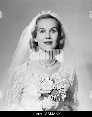 1950ER JAHRE PORTRAIT FRAU BRAUT PERLENKETTE WEIßE HANDSCHUHE HOLDING KLEINEN BLUMENSTRAUß BLICK IN DIE KAMERA Stockfoto