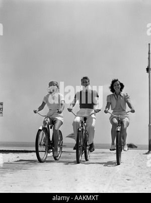 1940ER JAHRE MANN ZWEI FRAUEN BIKE-STRANDPROMENADE Stockfoto