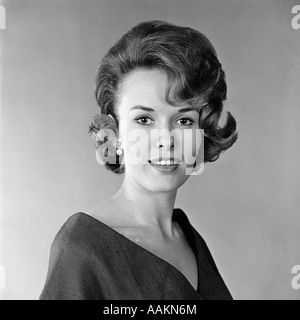 1960ER JAHRE PORTRÄT LÄCHELNDE FRAU BLICK IN DIE KAMERA MODISCHE FRISUR GEHÄNSELT Stockfoto