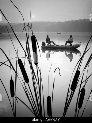 1980ER JAHREN ZWEI MÄNNER IM BASS FISHING BOAT AUF RUHIGEM WASSER SEE ROHRKOLBEN IM VORDERGRUND Stockfoto